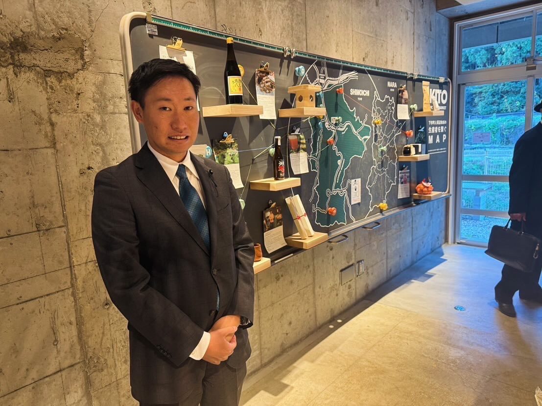 地域の特産品展示の前に立つ川口信
